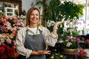 Smiling woman florist small business owner standing in own floral store and waiting for client photo