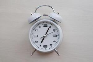 White retro alarm clock on textured background with copy space. Clock face. photo