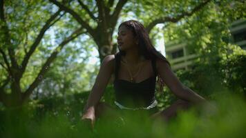 A woman is calmly meditating in a serene natural environment surrounded by greenery and trees video