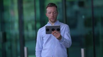 A person is holding a digital device while in a modern urban setting full of life video