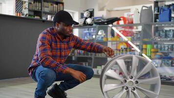 Portrait of a seller with a wheel disk in auto parts shop video