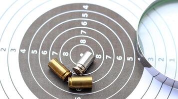 Empty bullet casing on a shooting target, with a part of magnifying glass, evoking the concept of crime scene investigation and unraveling mysteries. photo