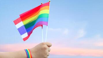 Cut out of hand holding both the LGBT flag and Thailand flag, set against blue sky background with clipping paths. The symbolizing unity, diversity, and inclusion. photo