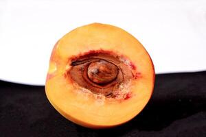 Beautiful peach half with seed isolated on black and white background . photo