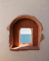 A window in a wall with a view of the ocean photo
