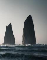 Two large rock formations in the ocean photo