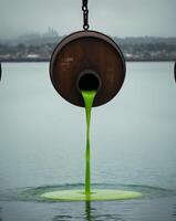 A green liquid is being poured into a barrel photo