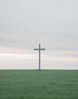 A cross stands in the middle of a field photo