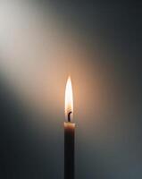 A single candle is lit in the dark photo