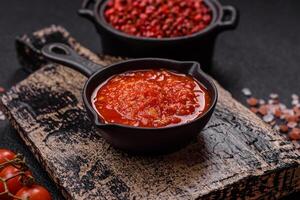Delicious hot spicy red sauce with salt and spices in a ceramic bowl photo