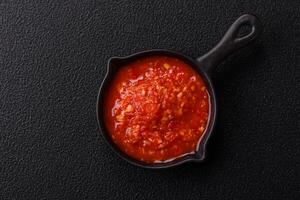 Delicious hot spicy red sauce with salt and spices in a ceramic bowl photo