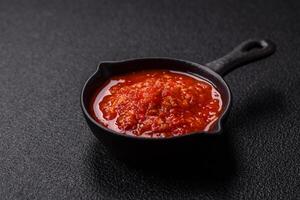 Delicious hot spicy red sauce with salt and spices in a ceramic bowl photo