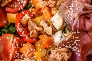 Appetizing salad with prosciutto, pumpkin, cheese and tomatoes photo