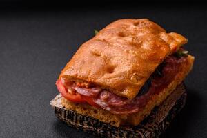 Focaccia with salami, cheese, tomatoes, arugula, salt, spices and herbs photo