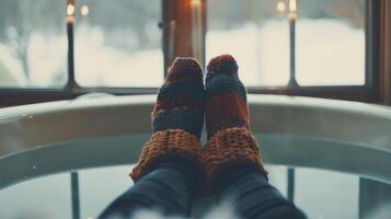 A person sitting in the bathtub with their hands and feet submerged while wearing a warm beanie to keep their head warm photo