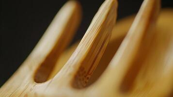 A zoomedin shot of a bamboo fork revealing the smooth and polished surface of the utensil. Each tine has a slight curve creating a gentle yet effective scooping shape photo