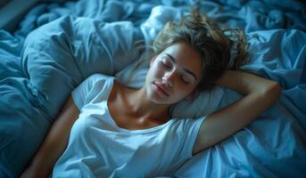 A woman is sleeping on a bed with her head on a pillow. She is smiling and she is in a relaxed state. photo