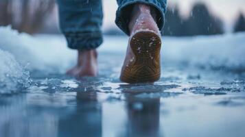 A closeup of feet stepping gingerly into a frozen lake the person determined to reap the benefits of mindfulness and cold immersion photo