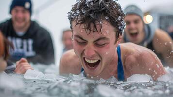 A man grimacing as he sinks into a large tub of ice cubes his friends cheering him on from the side for the winter ice bath challenge photo