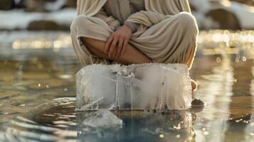 An individual wrapped in a towel sitting crosslegged on a block of ice for a refreshing cooldown photo