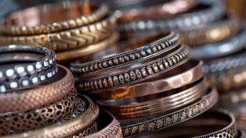 A stack of handcrafted bangles showcase an array of textures from smooth polished metal to intricate hammered designs and delicate filigree work photo