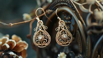 A pair of dainty earrings feature intricate wire wrapping with tiny gemstones peeking through the intricate design photo