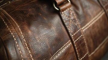 A closer look at a leather duffel bag reveals the strength and durability of the material. The grain is tightly packed and the stitching is done with thick reinforced thread to ensur photo