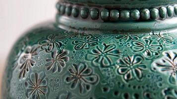 The intricate handcarved details on a ceramic vase featuring a glossy emerald green glaze that adds a touch of elegance to any room photo