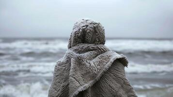 A person wraps themselves in a thick fluffy towel after emerging from a freezing dip in the ocean their body humbled but their mind strengthened photo