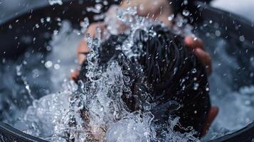 A person dunking their head into a bucket of ice water part of the preparation for the winter ice bath challenge photo