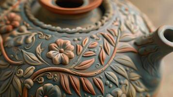 The intricate details of a clay teapot featuring handpainted floral designs and a raised relief of delicate leaves and vines photo