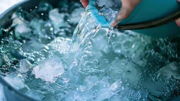 A person using a bucket to pour the melted ice water out of the bath making space for more ice photo