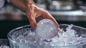 A hand reaching into an ice bath to grab an ice ball infused with calming lavender oil photo