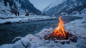 A sacred fire burning brightly in the midst of snowy mountains with people participating in a spiritual ceremony that involves taking ice baths in a nearby river photo