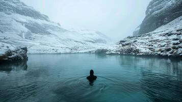 A lone figure submerged in a freezing mountain stream their breath visible in the cold air photo