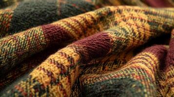 A detailed shot of a vintage plaid fabric featuring a variety of earthy tones such as burgundy forest green and mustard. The textured weave of the fabric is visible creating a coz photo