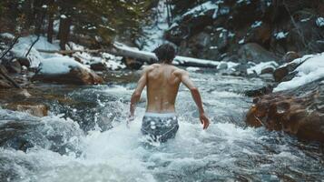 A man in swim trunks bravely faces his fears and takes a dip in the icy waters of a mountain stream determined to push his bodys limits and adapt to the new seasonal changes photo