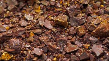 A closeup image of a pile of deep red and brown es with flecks of yellow and green peeking through. The co texture of the es is visible with some pieces appearing to be ground whil photo