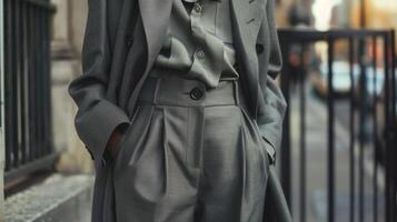 A chic and sophisticated allgrey outfit consisting of a buttonup blouse wideleg pants and a tailored coat. The monochrome color scheme adds to the overall polished and elegant look photo