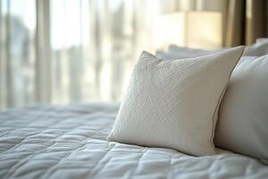 White pillow rests on a made bed. photo