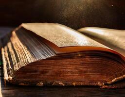 Close-up of an old, weathered book with sunlight highlighting dust particles floating above its yellowed pages. photo
