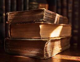 A stack of aged, worn books illuminated by warm sunlight, highlighting the textured pages and worn bindings in a cozy setting. photo