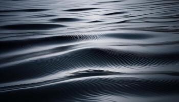 Close-up of calm water surface with soft rippling waves, showcasing smooth textures and gentle reflections in dark tones. photo