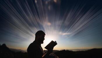 A man reading a book outdoors at sunrise, with dramatic light rays emanating from the background, symbolizing knowledge and inspiration. photo