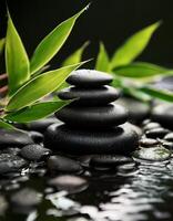 Stacked black spa stones with bamboo leaves surrounded by water, creating a serene and calming zen-like atmosphere for relaxation. photo