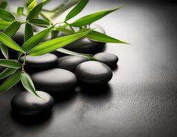 Smooth black stones and fresh green bamboo leaves create a calming and peaceful Zen-inspired spa atmosphere on a textured surface. photo