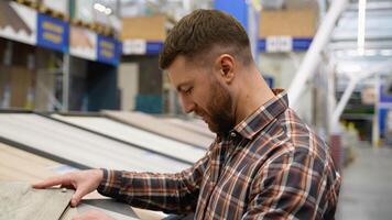 A man looks at different types and colors of floor coloring in a store video