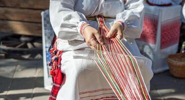 Process of weaving. Hands of a woman as they carefully manipulate colorful threads on a loom. Traditional clothing adds a touch of cultural significance, suggesting a connection to artisan skills. photo