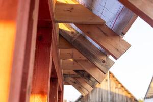 lose-up of a wooden roof frame during construction. The wooden planks are arranged in a grid pattern and supported by beams, creating a sturdy foundation for the roof. photo