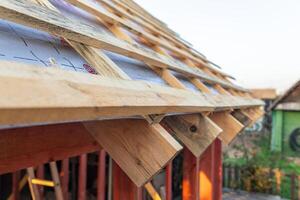 lose-up of a wooden roof frame during construction. The wooden planks are arranged in a grid pattern and supported by beams, creating a sturdy foundation for the roof. photo
